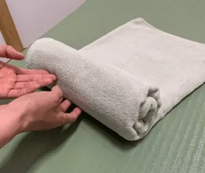 【タオル枕の作り方】
1.用意したタオル枕を半分に折り、縦長の状態にします。
2.端から「ふんわり」とまるめていきます。※強く硬く巻かないようにしましょう。
3.タオルの真ん中ぐらいまでふんわりと巻きます。
4.巻いた部分を優しく持ち上げてタオルの反対側の端に優しく置きます。
5.これで完成です。ふんわりとした所に首が乗るようにして仰向けで寝ます。